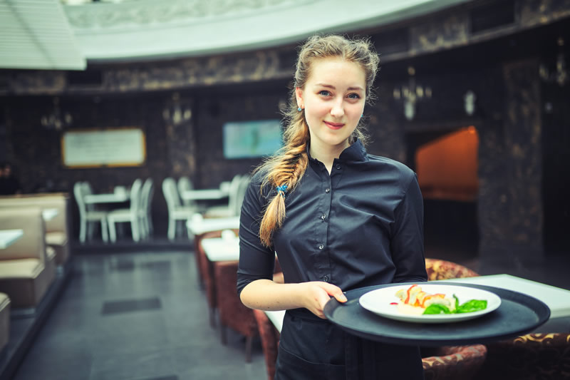 Kellnerin serviert in einem gehobenen Restaurant einen angerichteten Teller