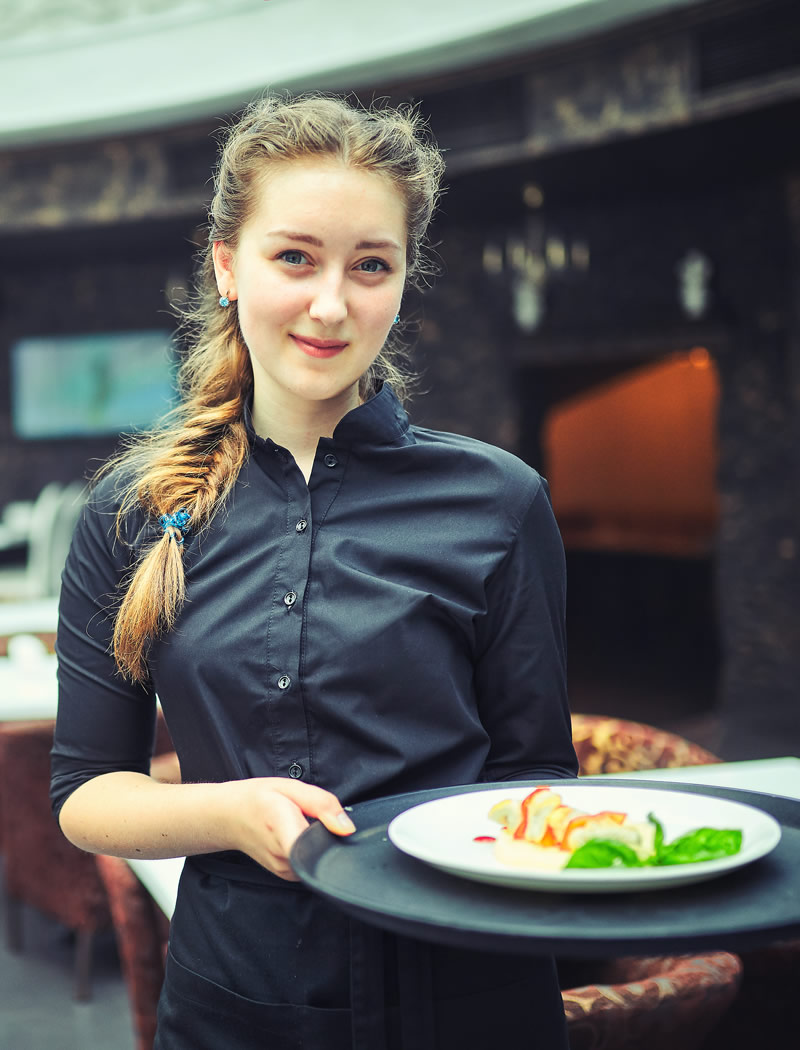 Kellnerin serviert in einem gehobenen Restaurant einen angerichteten Teller